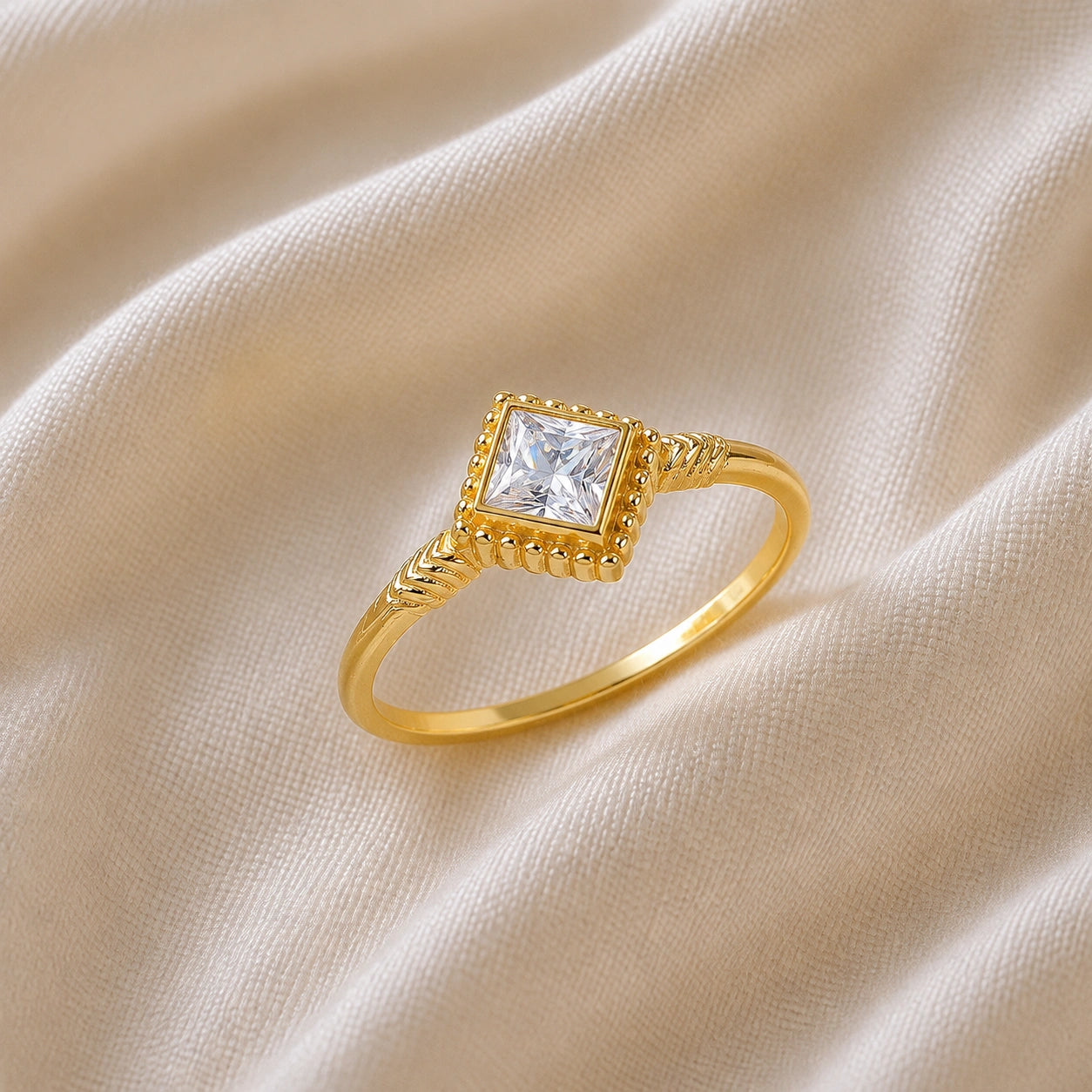 Princess_cut_ring_gold_plated_silver_with_square_cz_and_detailed_band_slightly_tilted_view_on_soft_fabric_background