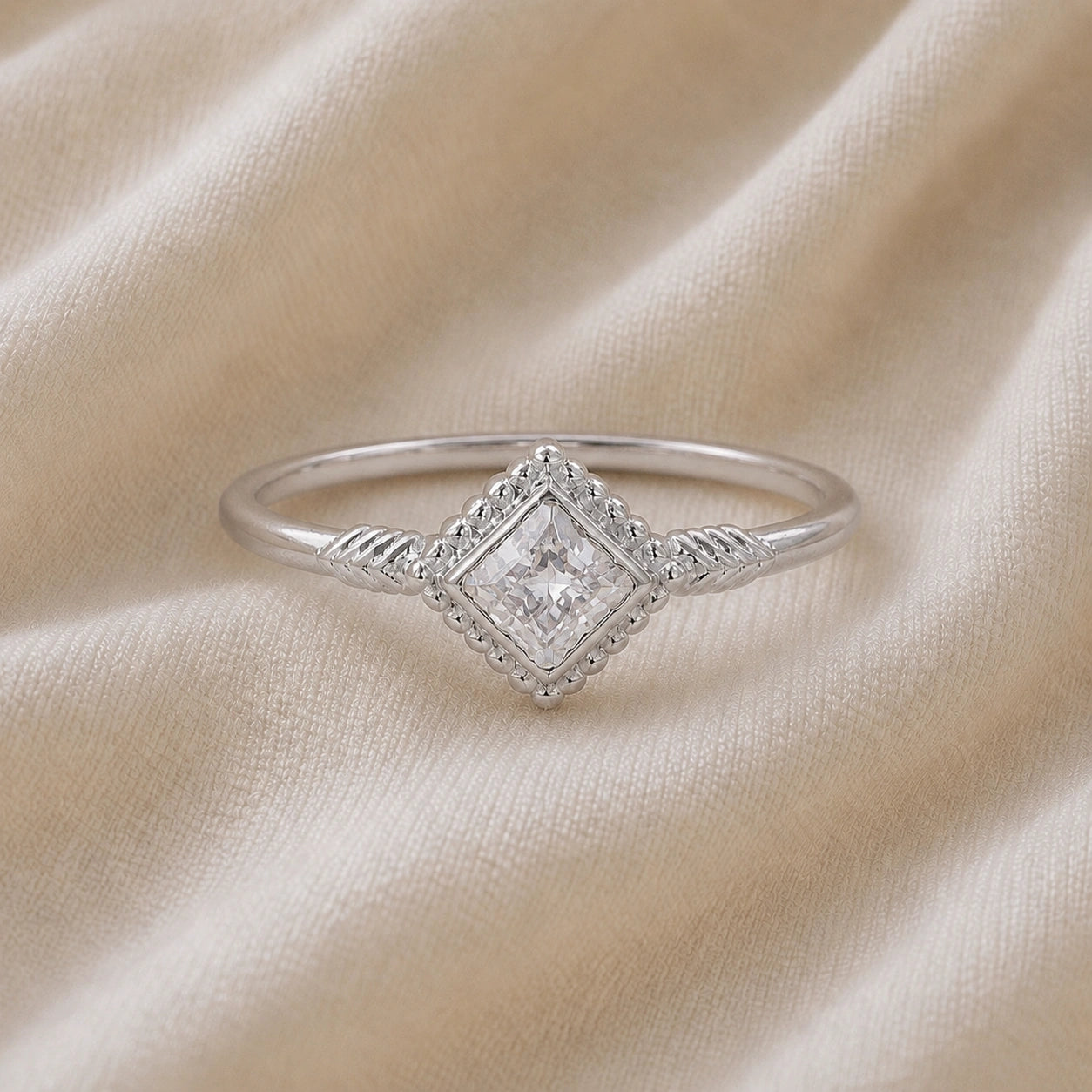 Princess_cut_ring_sterling_silver_with_square_cz_and_detailed_band_front_angle_view_on_soft_fabric_background