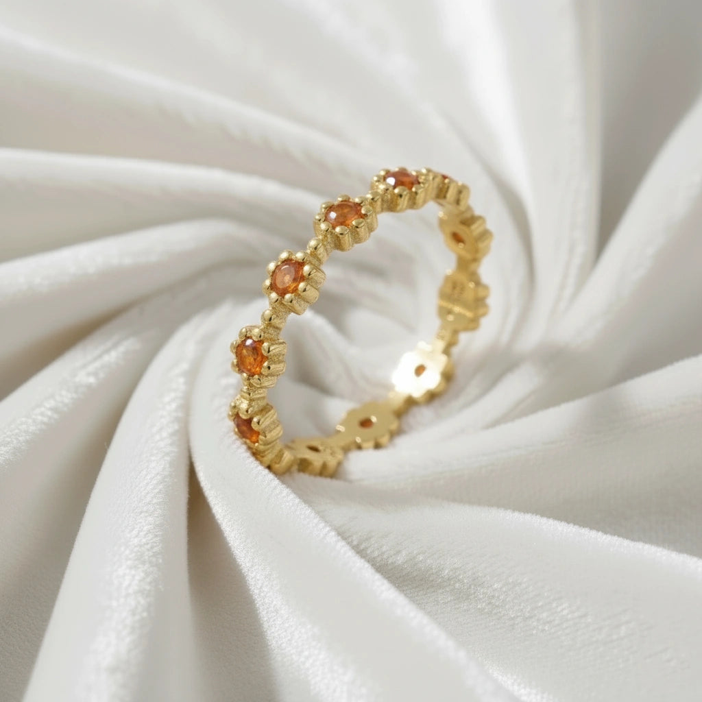 Gold carnelian ring featuring flower-shaped stones visible at an elevated angle on a messy off-white velvet cloth.
