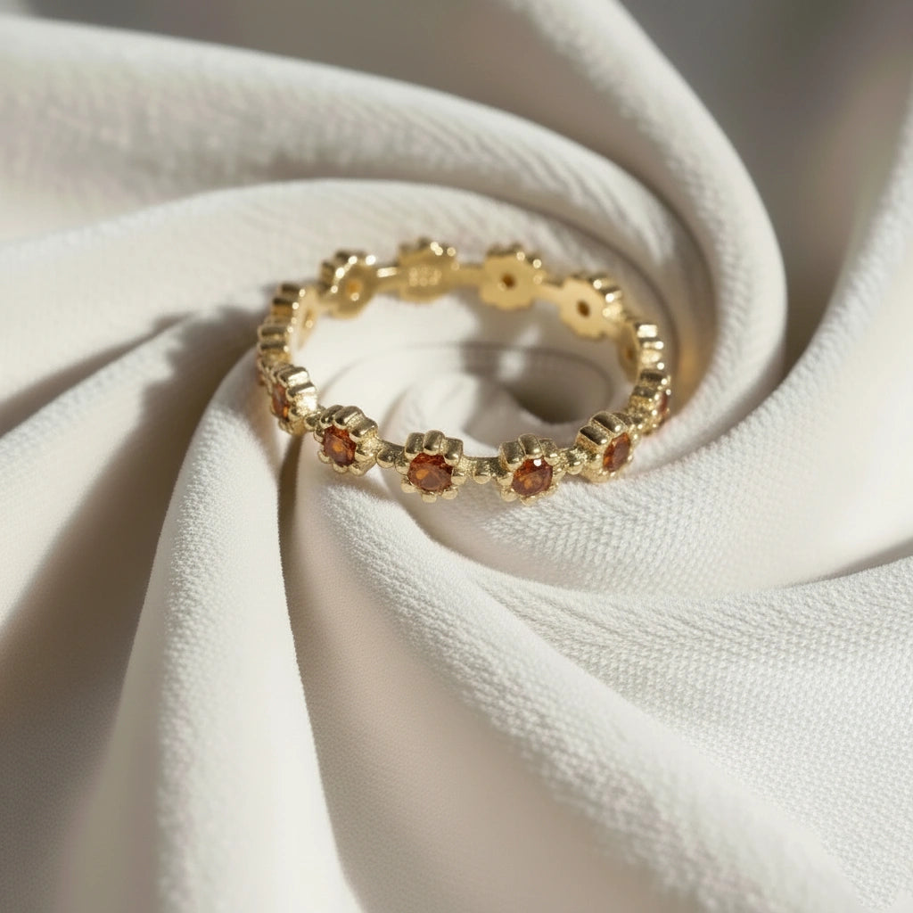 Gold carnelian ring featuring flower-shaped stones on a messy off-white velvet cloth at a slightly elevated angle.
