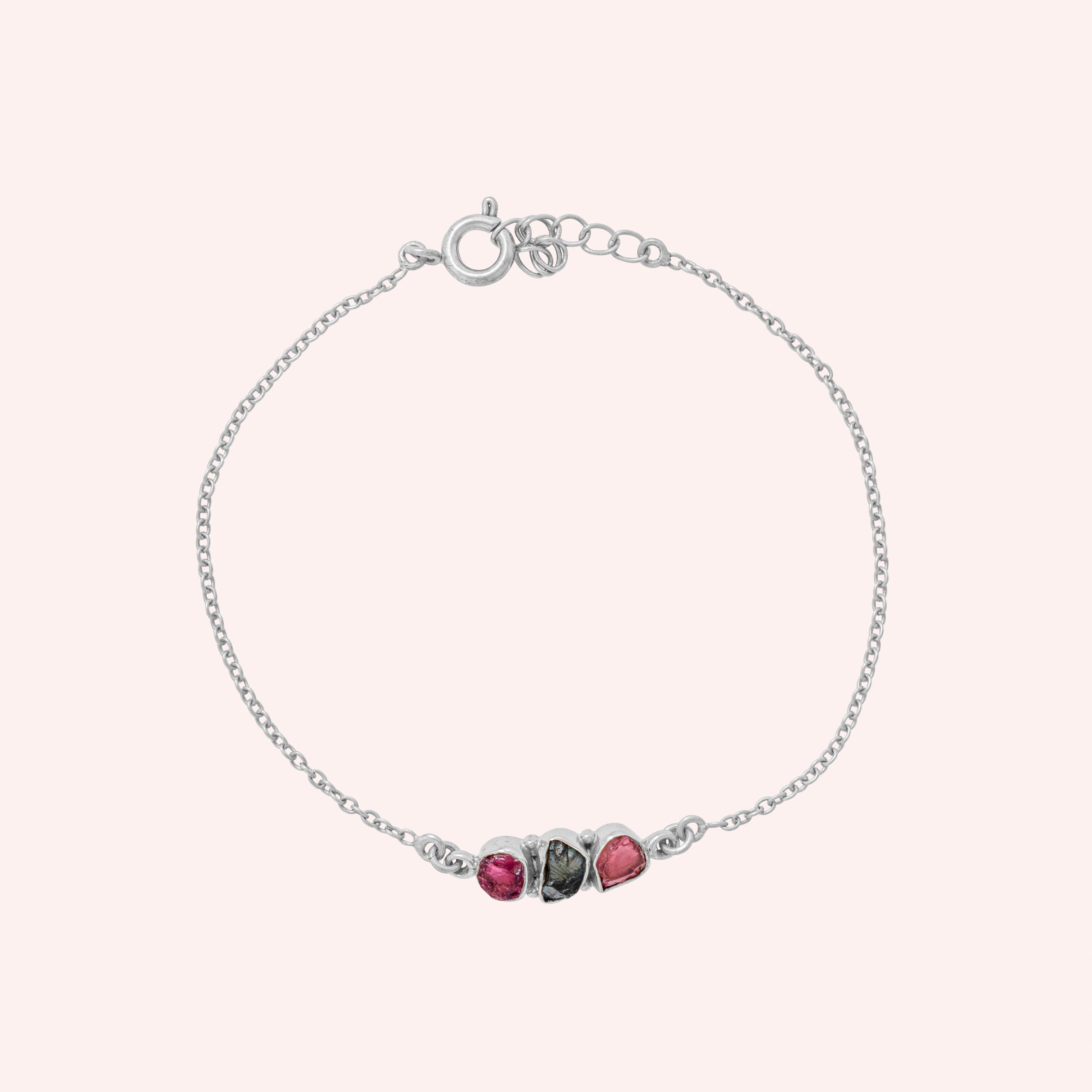 Chain_bracelet_in_sterling_silver_with_pink_and_green_tourmaline_stones_at_front_angle_view_on_solid_pink_background