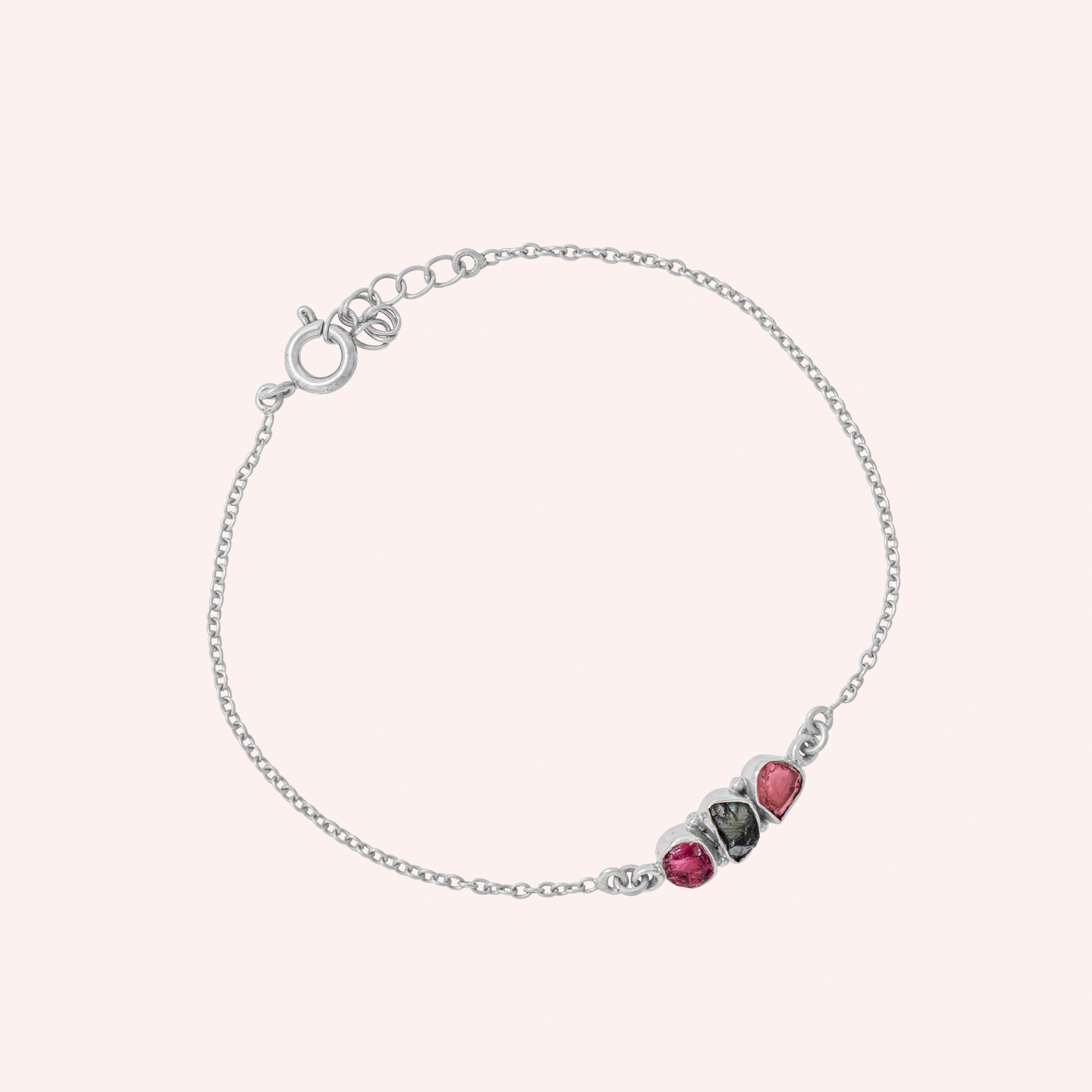 Chain_bracelet_in_sterling_silver_with_pink_and_green_tourmaline_stones_at_slight_angle_view_on_solid_pink_background