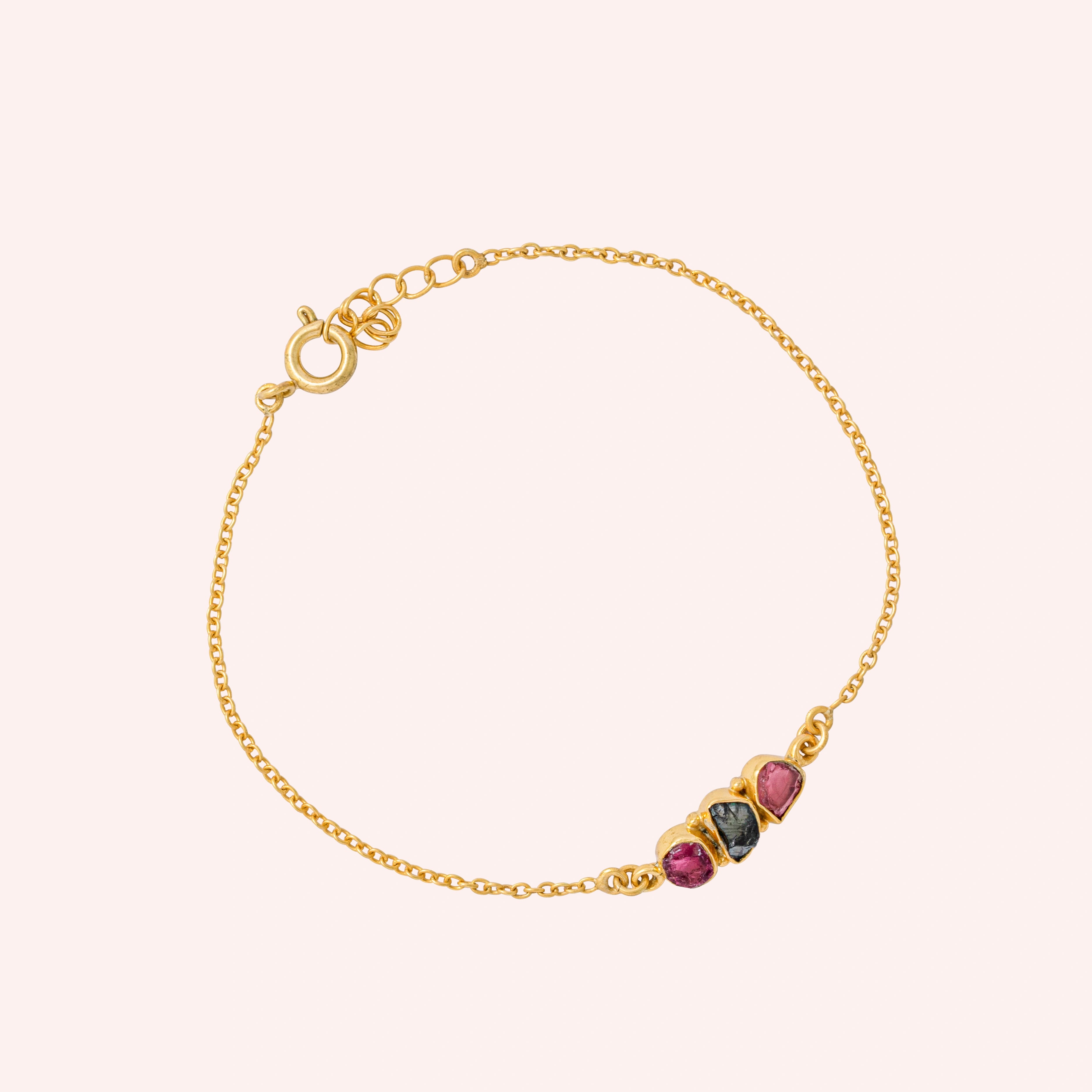 Chain_bracelet_in_gold_plated_silver_with_pink_and_green_tourmaline_stones_at_slight_angle_view_on_solid_pink_background