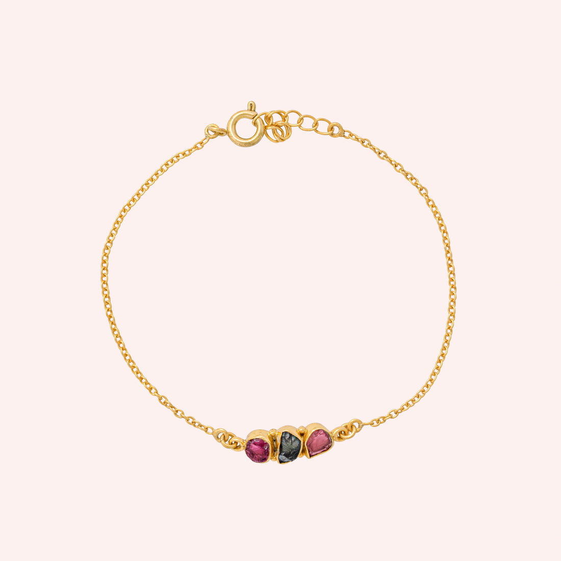 Chain_bracelet_in_gold_plated_silver_with_pink_and_green_tourmaline_stones_at_front_angle_view_on_solid_pink_background