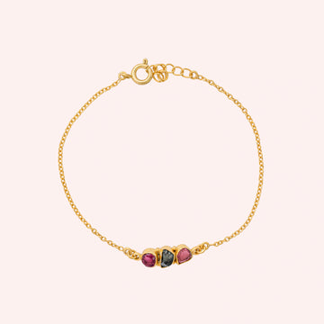 Chain_bracelet_in_gold_plated_silver_with_pink_and_green_tourmaline_stones_at_front_angle_view_on_solid_pink_background
