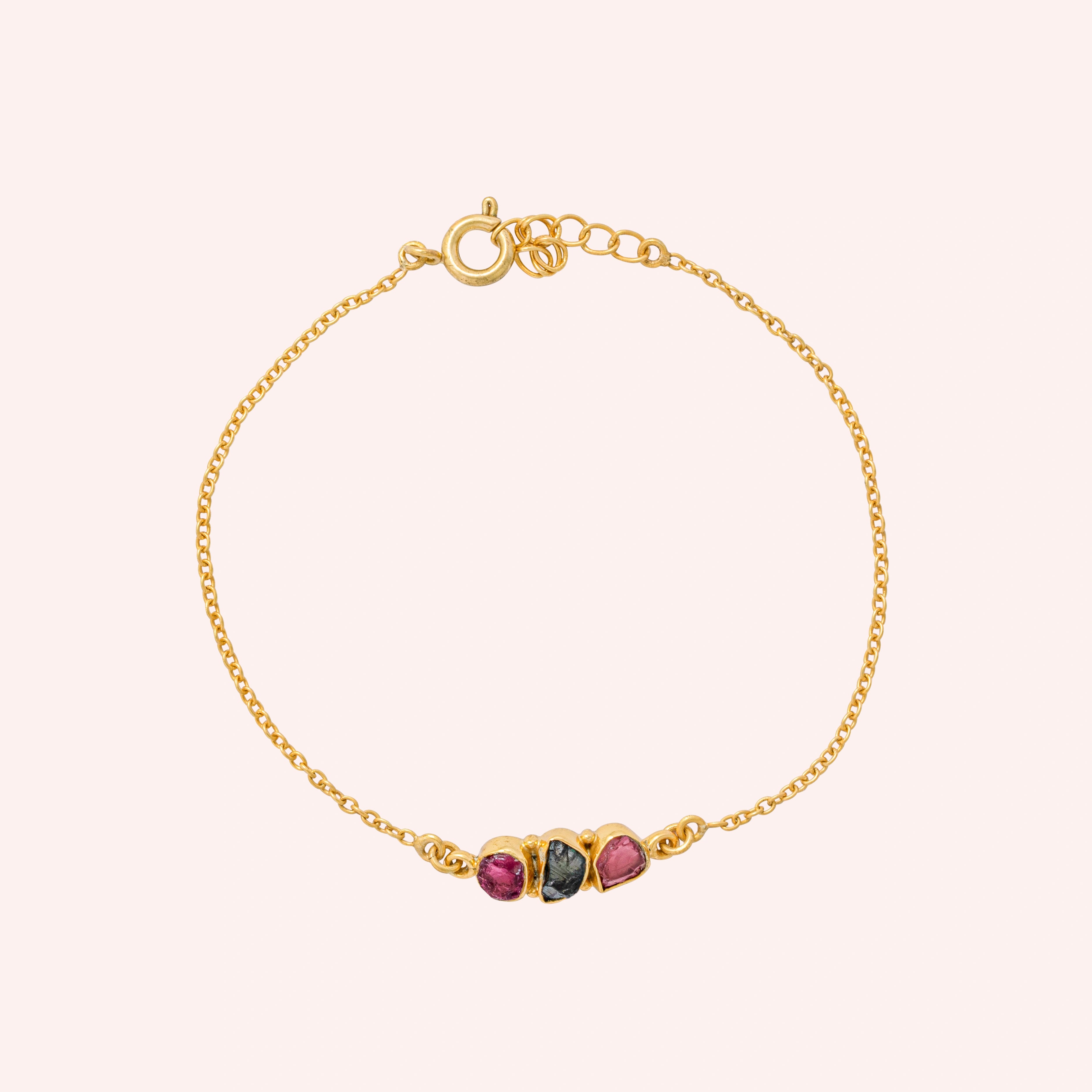 Chain_bracelet_in_gold_plated_silver_with_pink_and_green_tourmaline_stones_at_front_angle_view_on_solid_pink_background