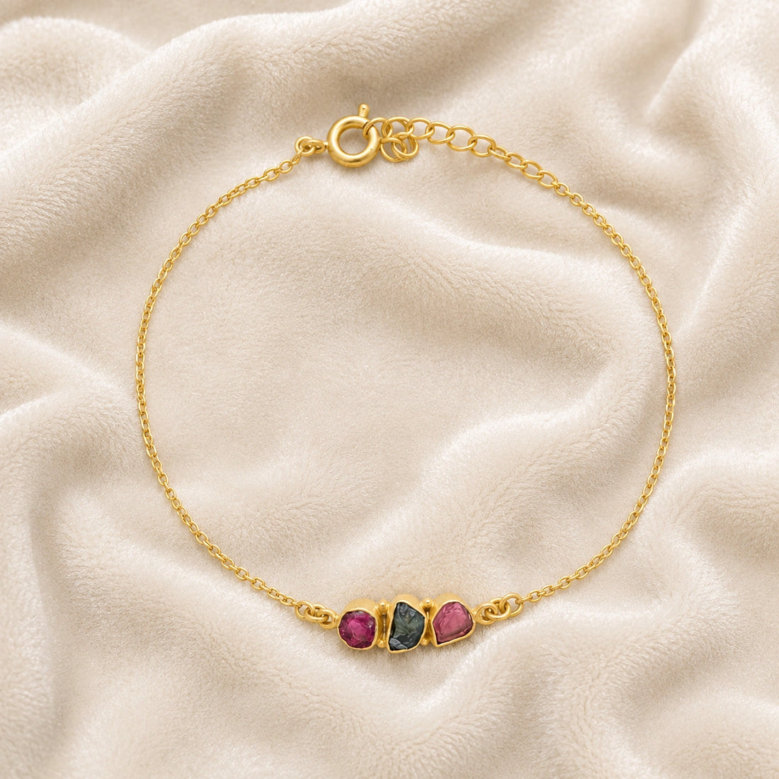 Chain_bracelet_in_gold_plated_silver_with_pink_and_green_tourmaline_stones_at_front_angle_view_on_soft_fabric_background