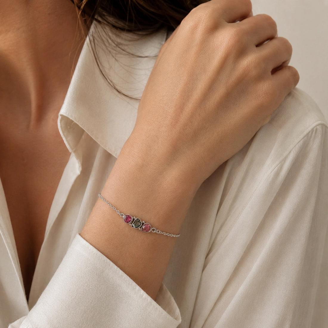 Chain_bracelet_in_gold_plated_silver_with_pink_and_green_tourmaline_stones_at_front_angle_view_on_soft_fabric_background