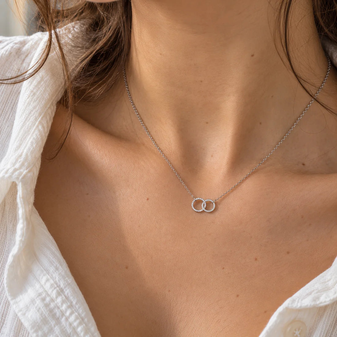 Charm_necklace_in_gold_plated_silver_with_interlock_circles_and_lab_grown_diamonds_at_side_angle_view_on_soft_fabric_background