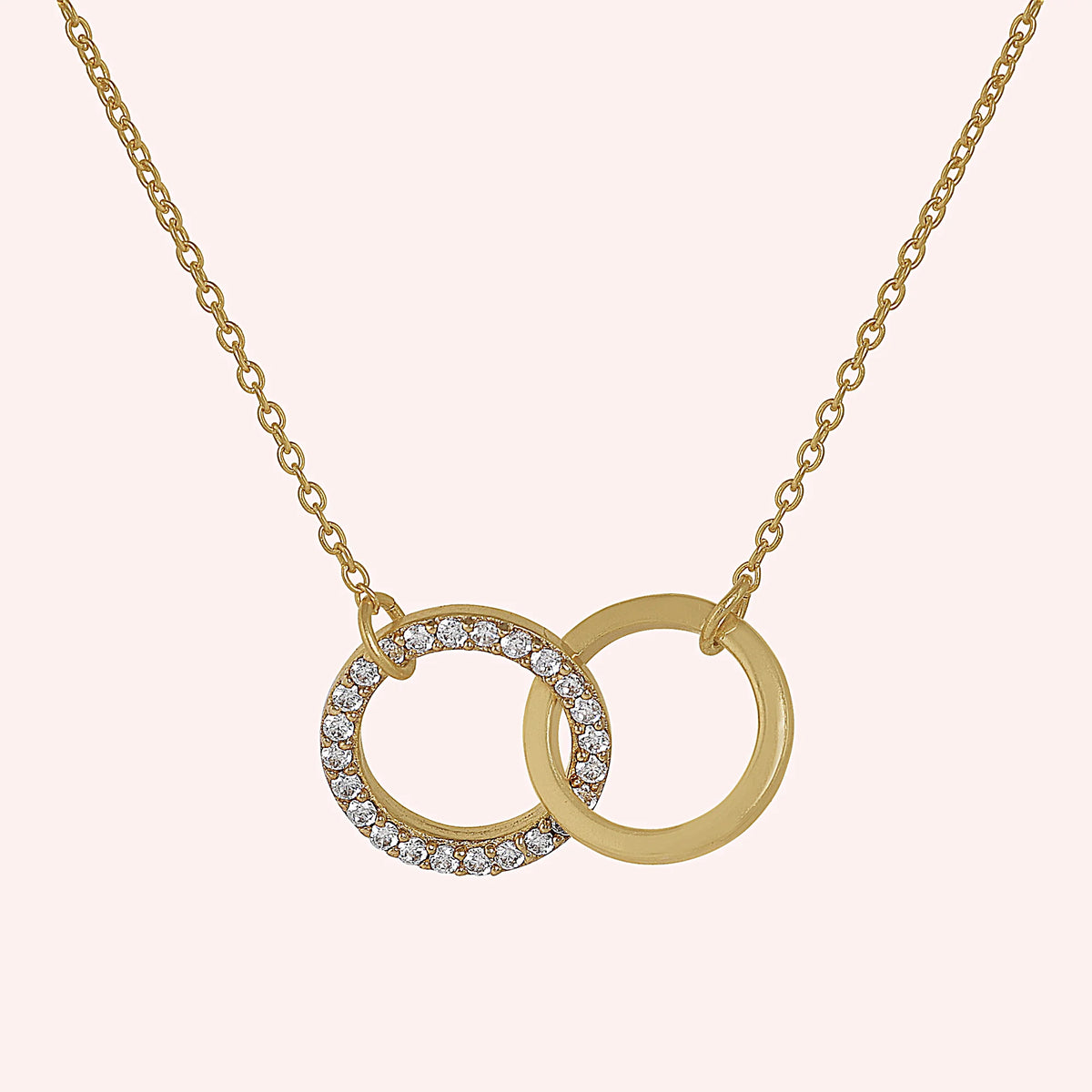 Charm_necklace_in_gold_plated_silver_with_interlock_circles_and_lab_grown_diamonds_at_front_angle_view_on_solid_pink_background