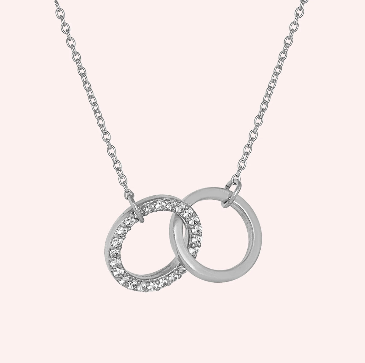 Charm_necklace_in_sterling_silver_with_interlock_circles_and_lab_grown_diamonds_at_side_angle_view_on_solid_pink_background