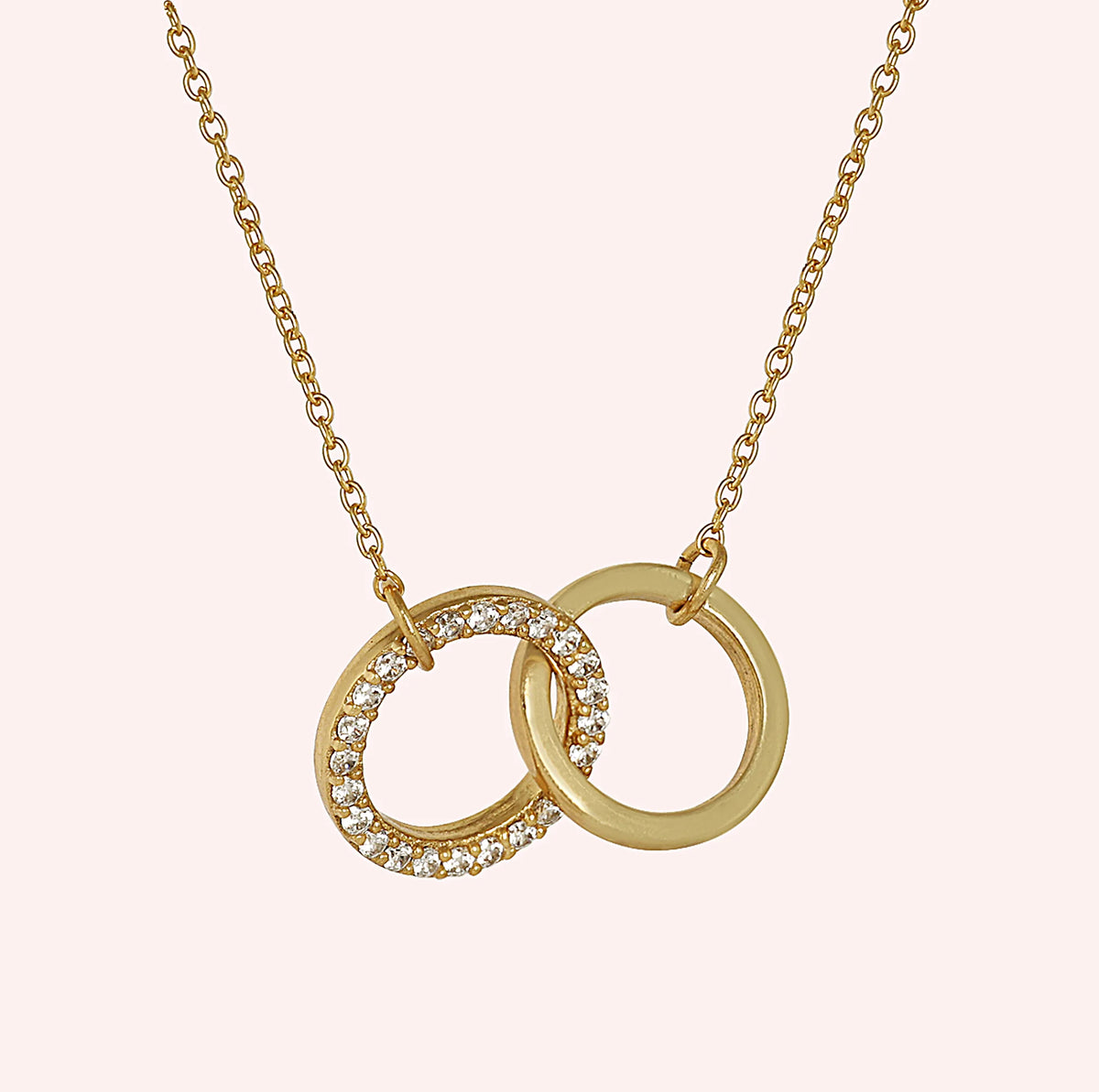 Charm_necklace_in_gold_plated_silver_with_interlock_circles_and_lab_grown_diamonds_at_side_angle_view_on_solid_pink_background
