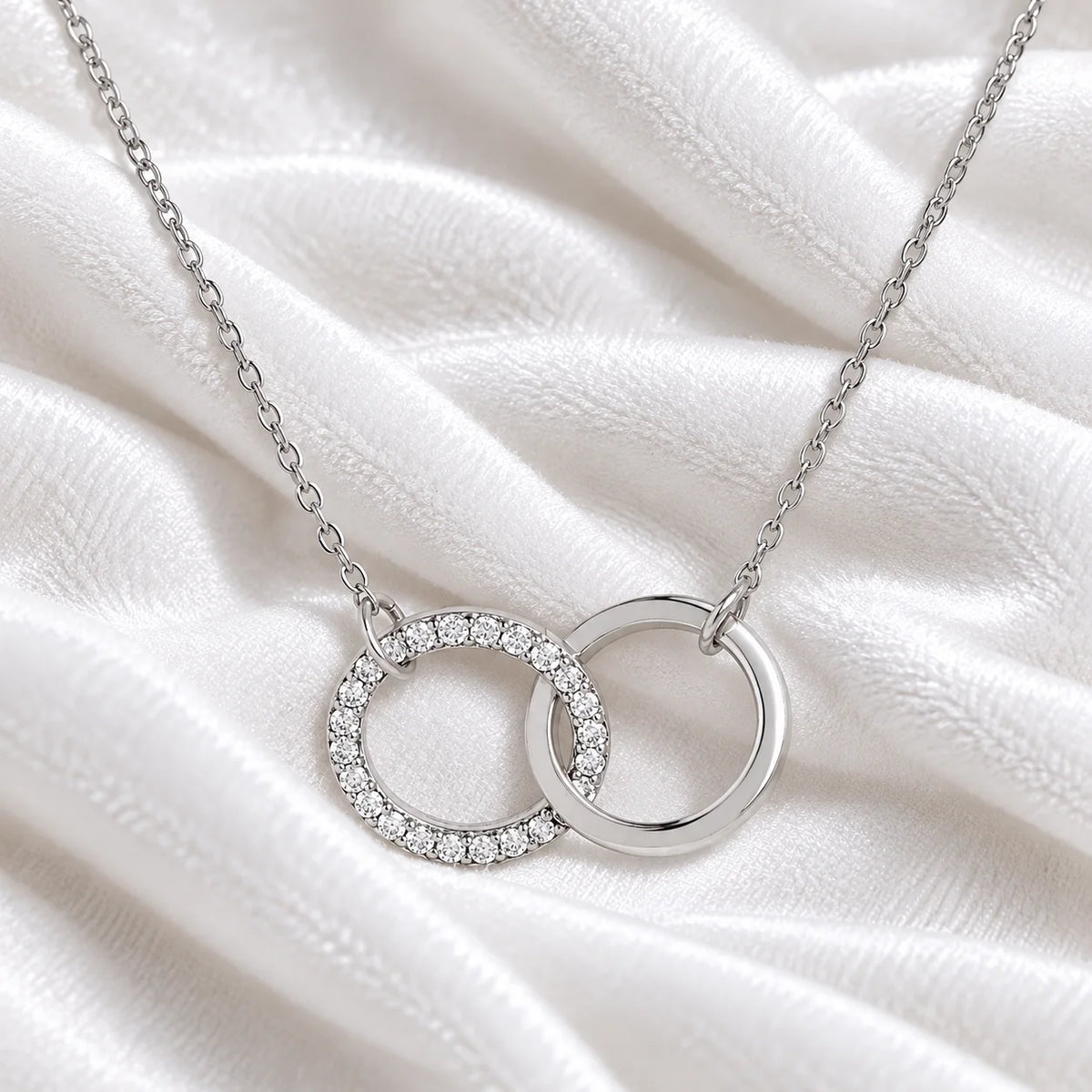 Charm_necklace_in_sterling_silver_with_interlock_circles_and_lab_grown_diamonds_at_front_angle_view_on_soft_fabric_background