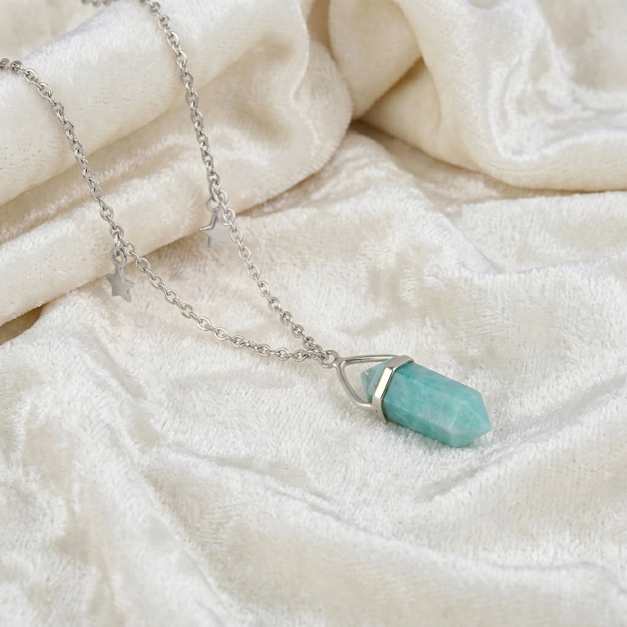 Charm_necklace_in_slightly_angled_view_with_sterling_silver_chain_star_charms_and_amazonite_stone_on_soft_fabric_background