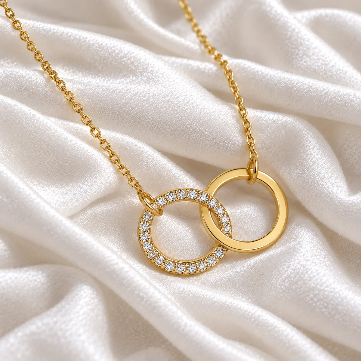 Charm_necklace_in_gold_plated_silver_with_interlock_circles_and_lab_grown_diamonds_at_side_angle_view_on_soft_fabric_background