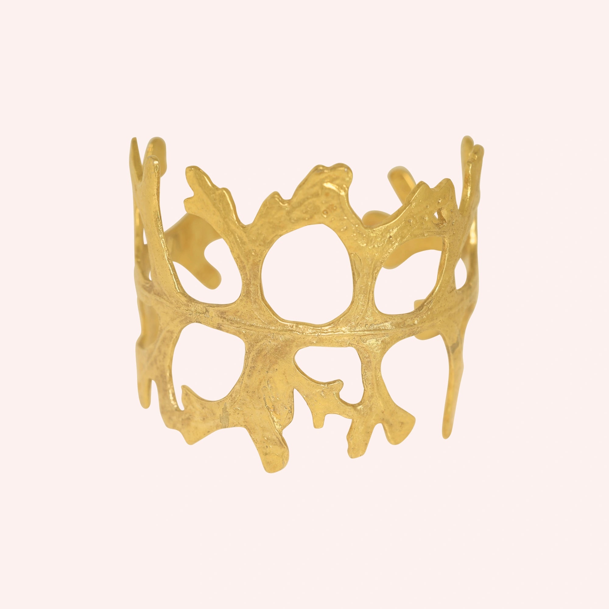 Chunky_bracelet_in_gold_plated_silver_showing_openwork_organic_adjustable_cuff_design_at_front_view_on_solid_pink_background