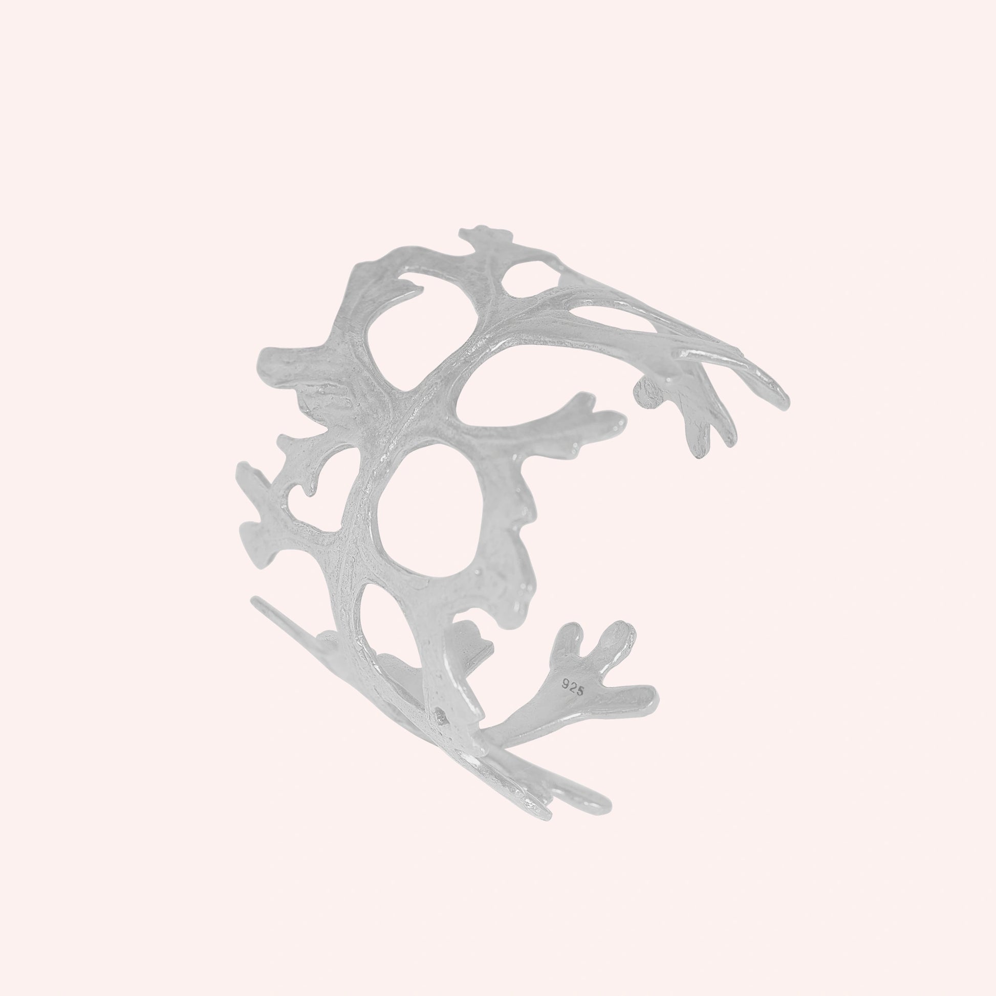 Chunky_bracelet_in_sterling_silver_showing_openwork_organic_adjustable_cuff_design_at_slight_view_on_solid_pink_background