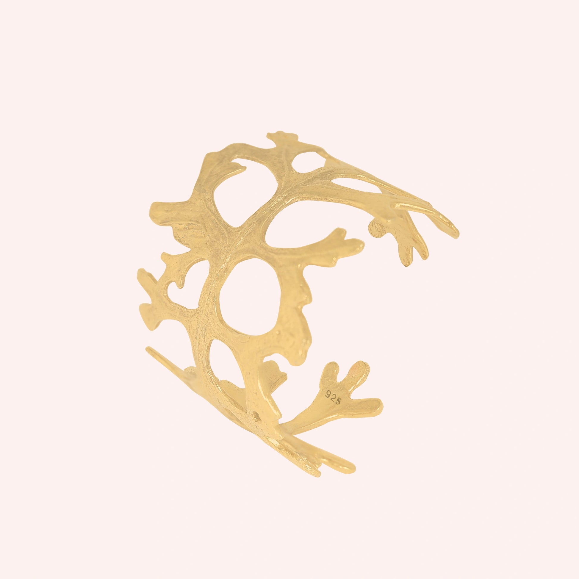 Chunky_bracelet_in_gold_plated_silver_showing_openwork_organic_adjustable_cuff_design_at_slight_view_on_solid_pink_background