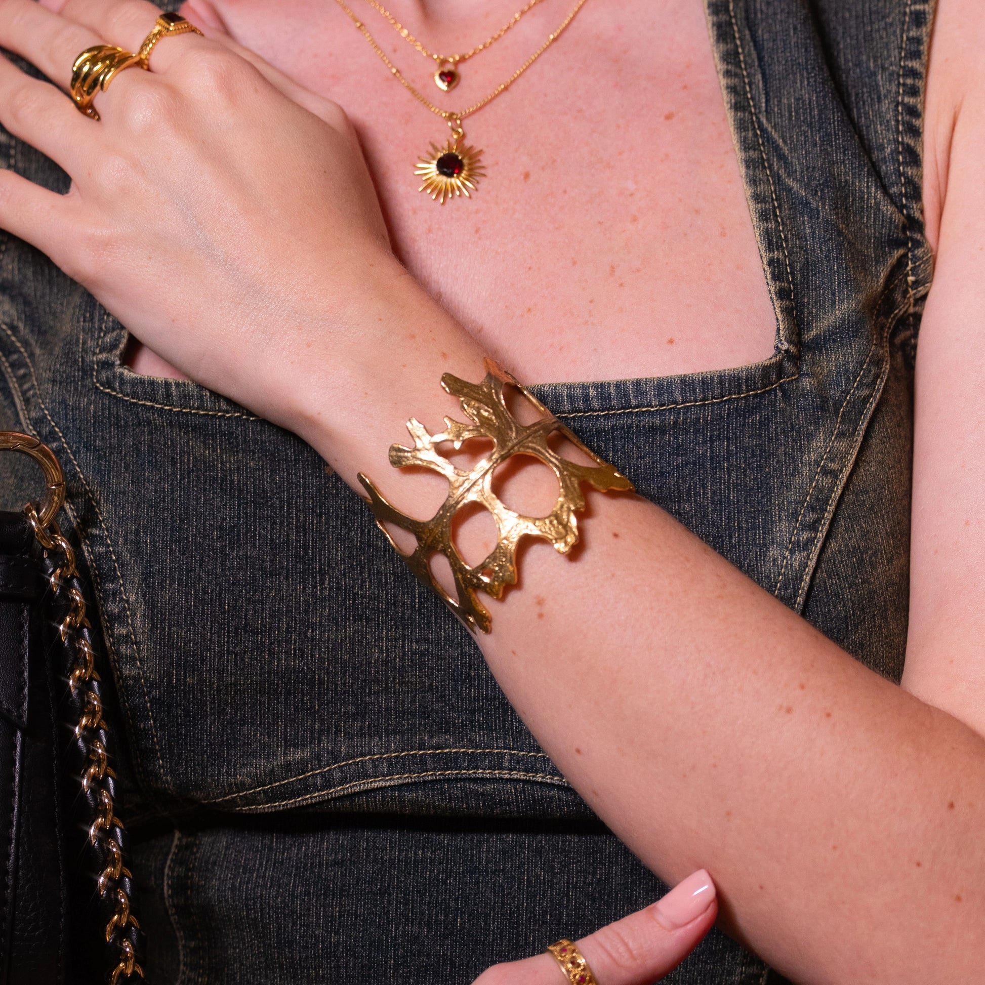 Chunky_bracelet_in_gold_plated_silver_showing_openwork_organic_adjustable_cuff_design_worn_by_a_model