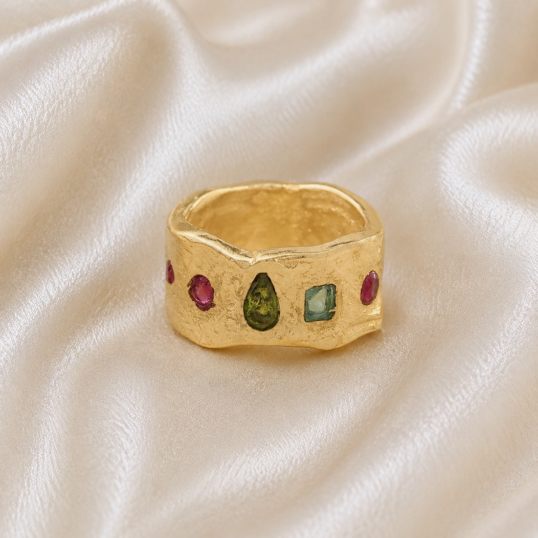 Chunky_ring_in_gold_plated_silver_at_front_angle_with_pink_tourmaline_peridot_and_blue_topaz_stones_on_a_soft_fabric_background