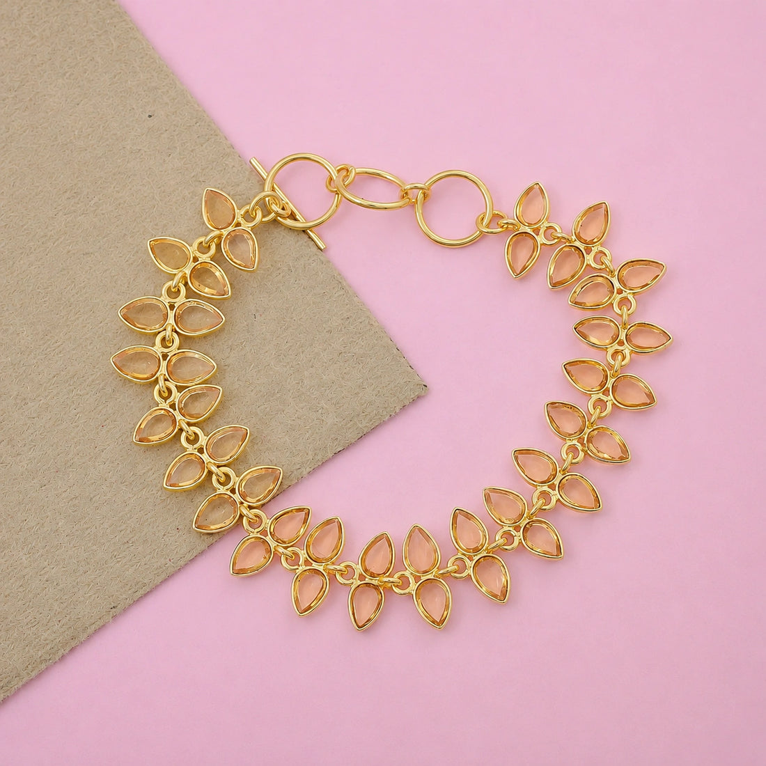Citrine_bracelet_in_gold_plated_silver_with_leaf_shape_citrine_design_at_front_angle_view_on_pink_background