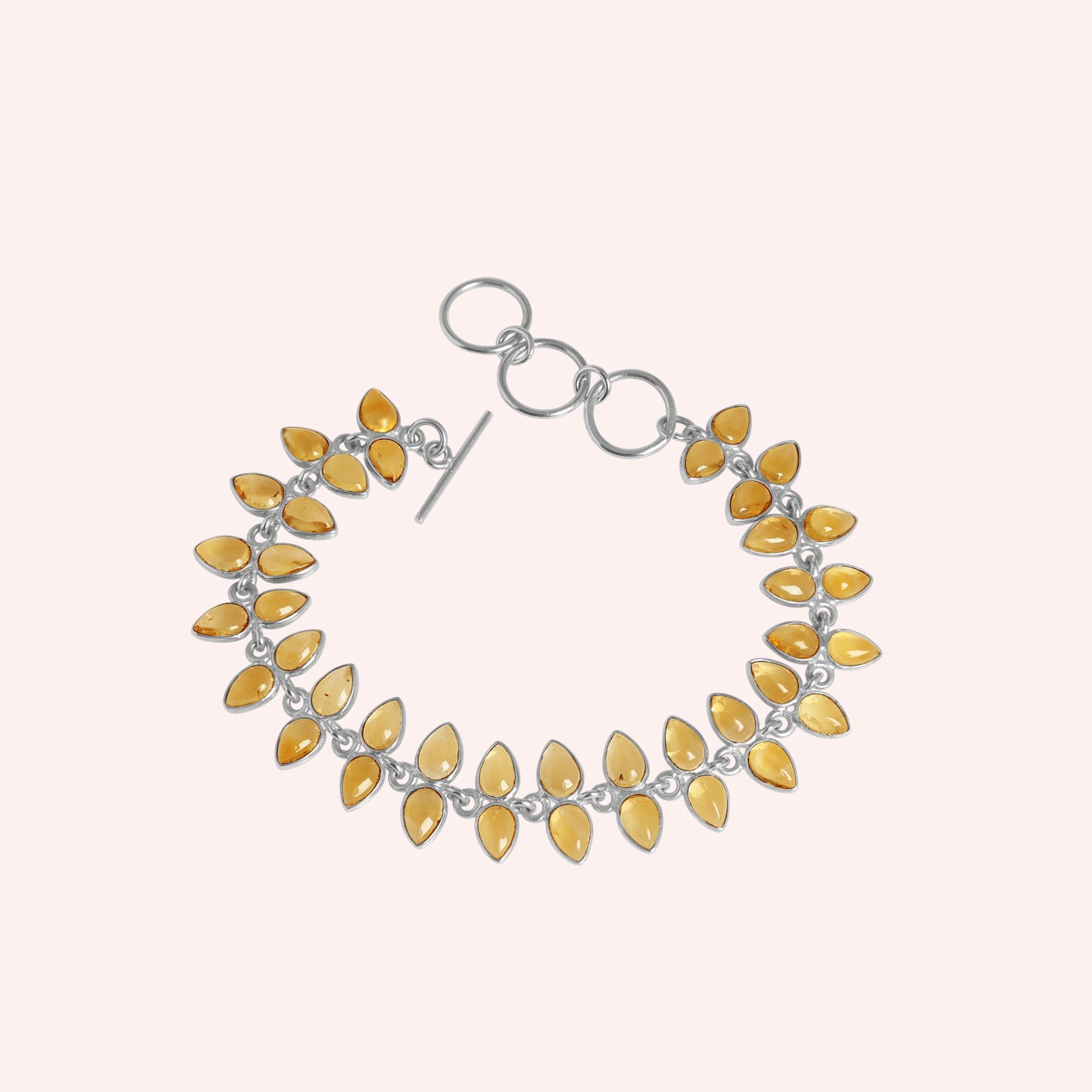 Citrine_bracelet_with_leaf_shaped_citrine_stones_in_sterling_silver_at_front_angle_view_on_solid_pink_background