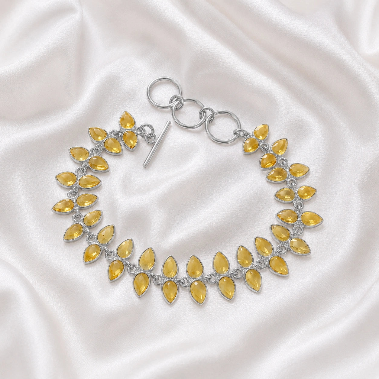 Citrine_bracelet_with_leaf_shaped_citrine_stones_in_sterling_silver_at_front_angle_view_on_soft_fabric_background