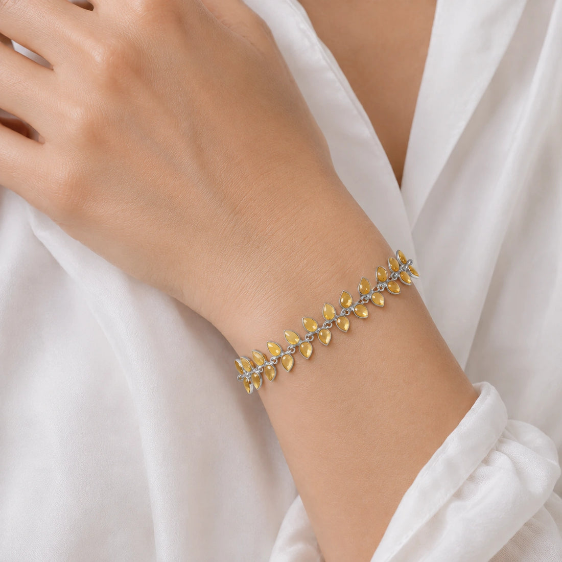 Citrine_bracelet_with_leaf_shaped_citrine_stones_in_gold_plated_silver_at_front_angle_view_on_soft_fabric_background