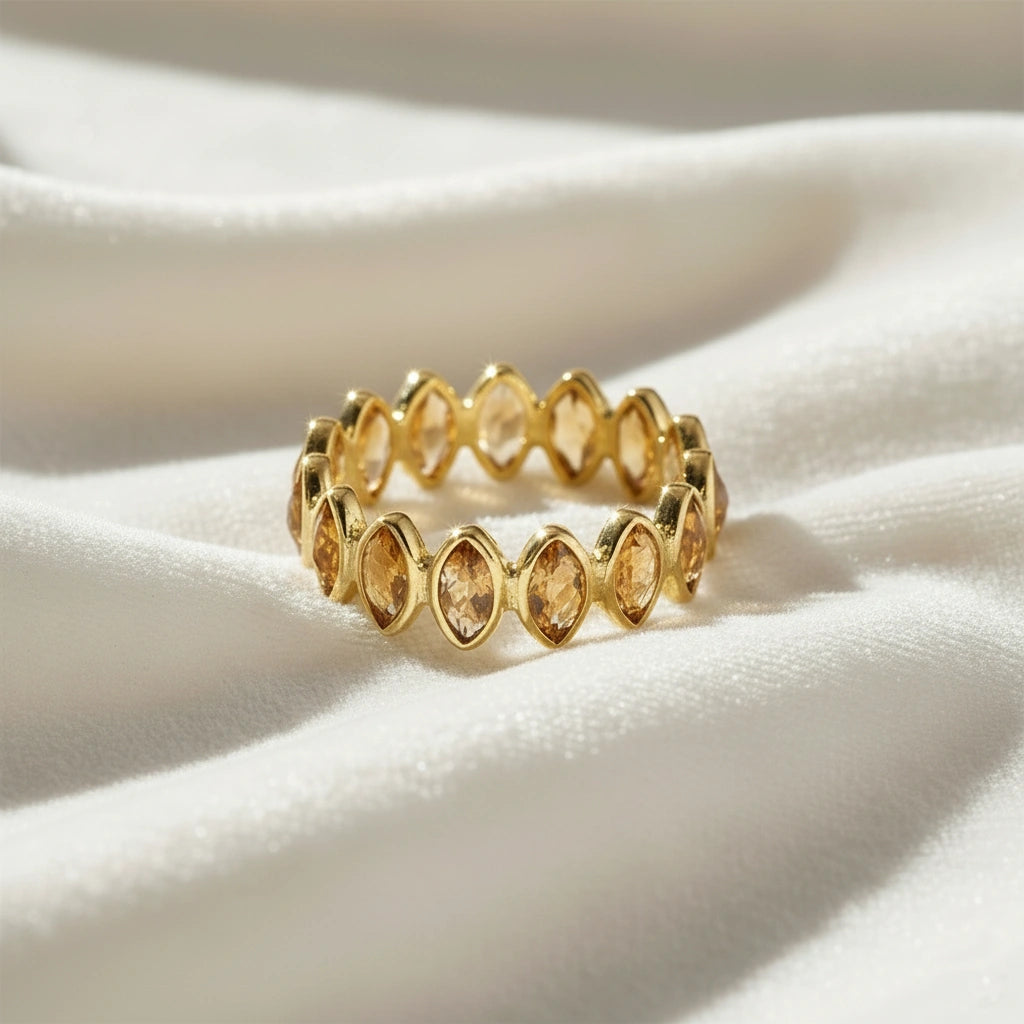Gold vermeil citrine eternity ring with marquise stones on a wrinkled off white velvet background straight angle view.