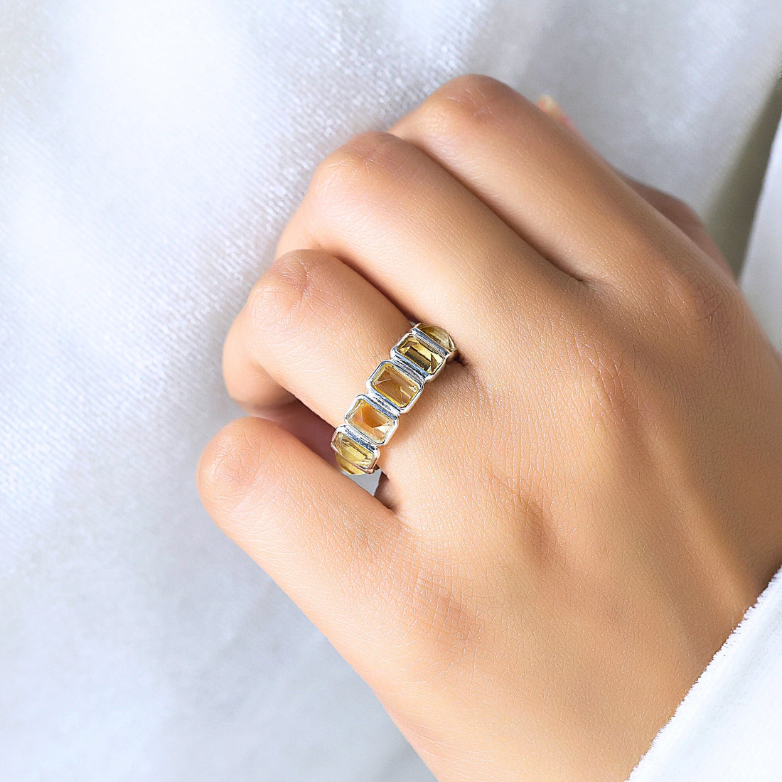 Angled close up shot of a sterling silver citrine ring on a white velvet fabric background showcasing rectangular citrine stones.