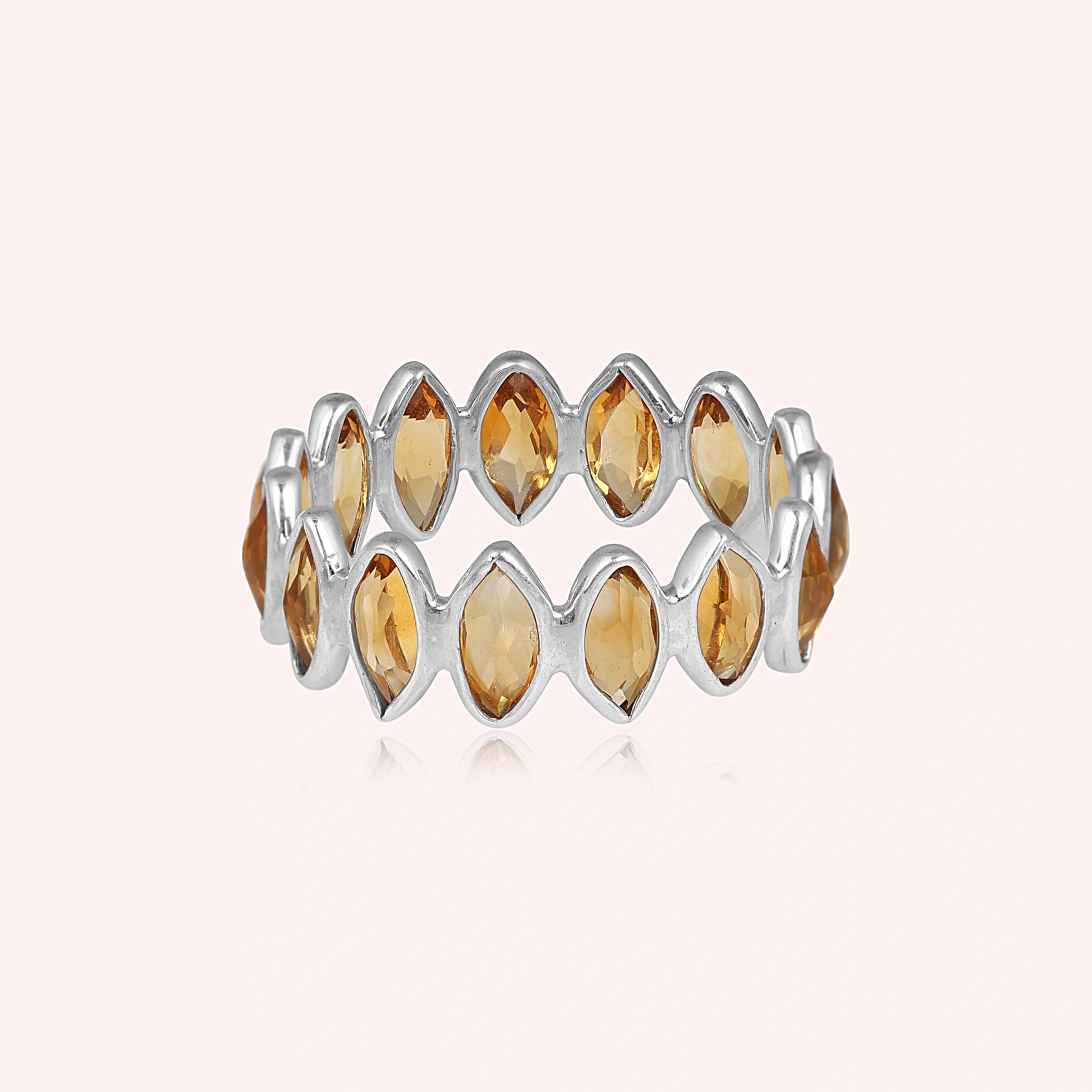 Sterling silver eternity ring featuring marquise citrine stones product focus on a light pink background straight angle view.
