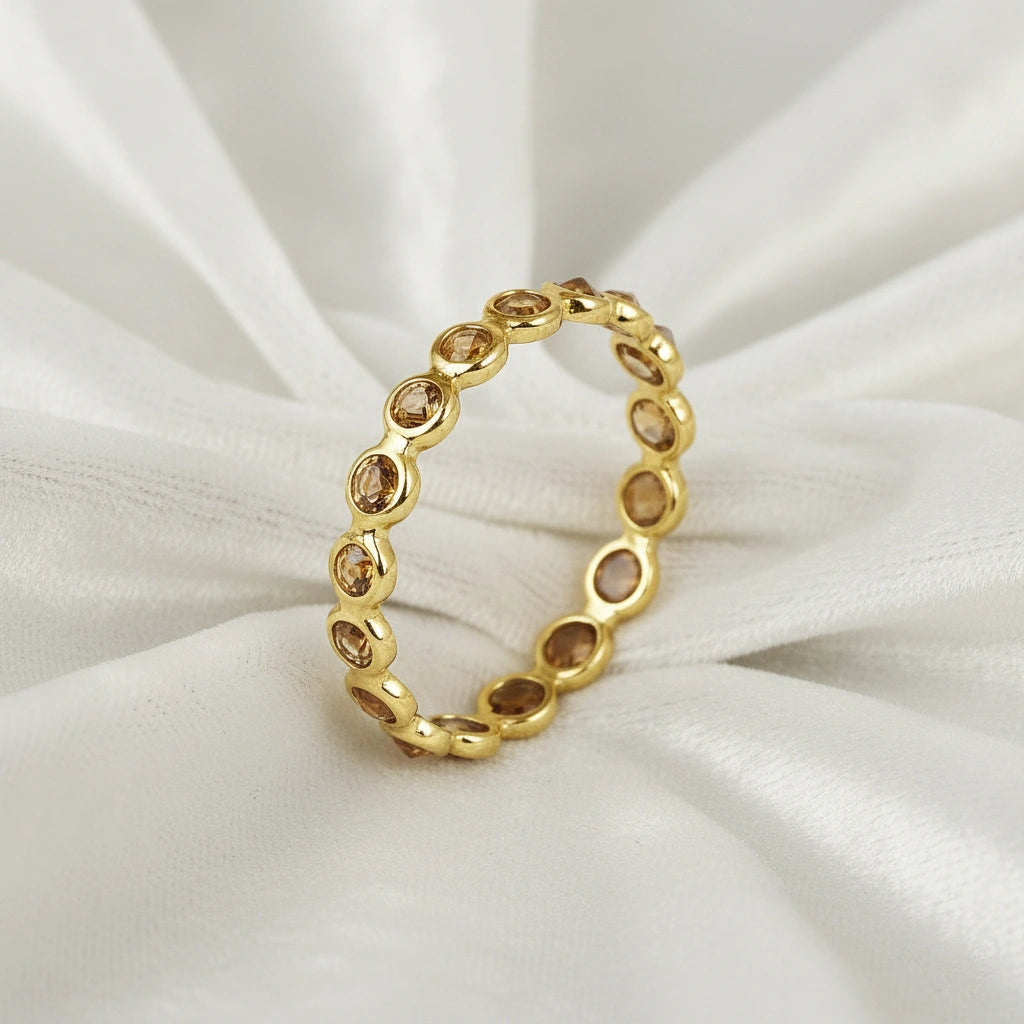 Angled close up shot of a gold-plated sterling silver citrine ring on a white velvet background with round cut yellow stones
