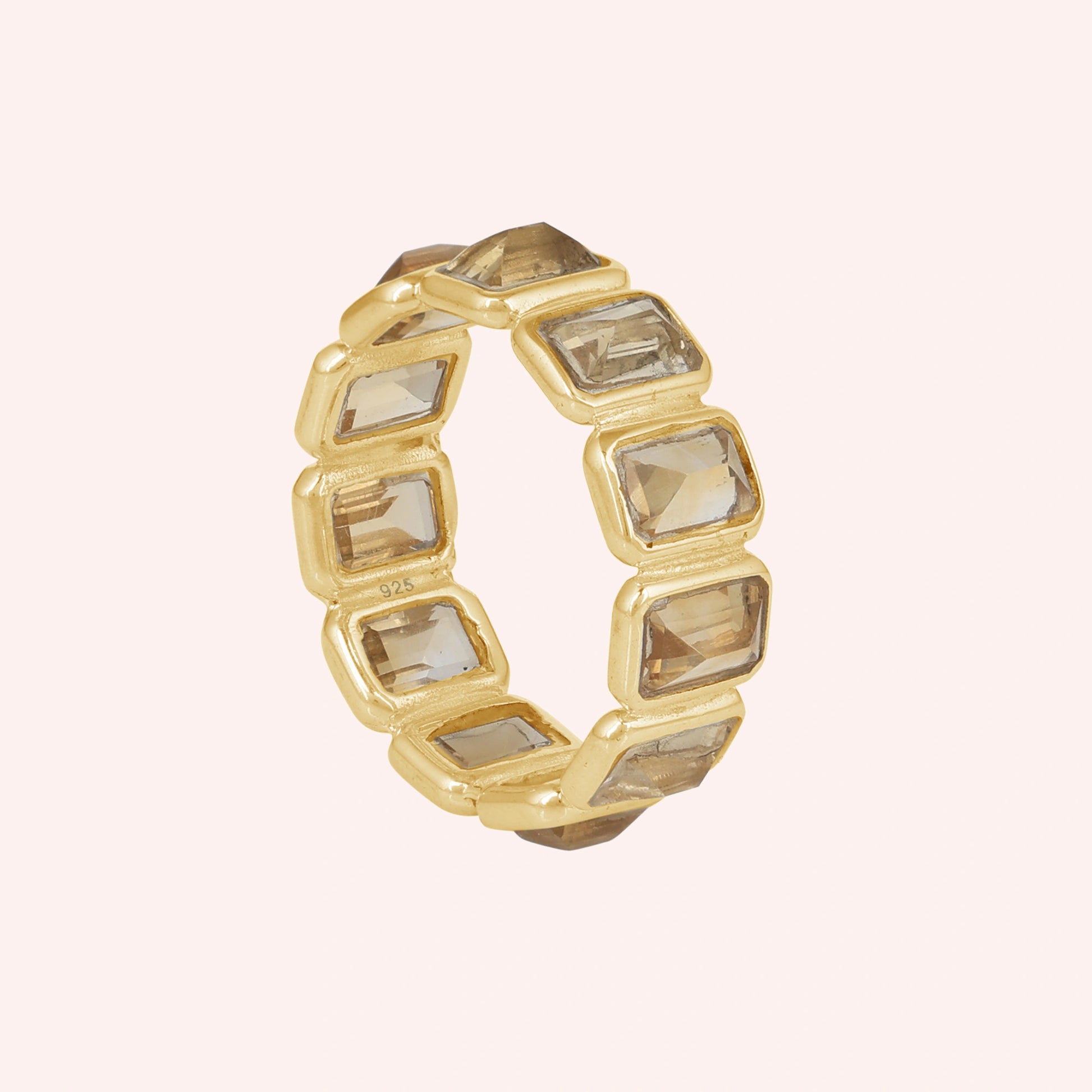 Angled shot of a sterling silver citrine ring on a light pink background showcasing rectangular citrine stones in a gold setting.