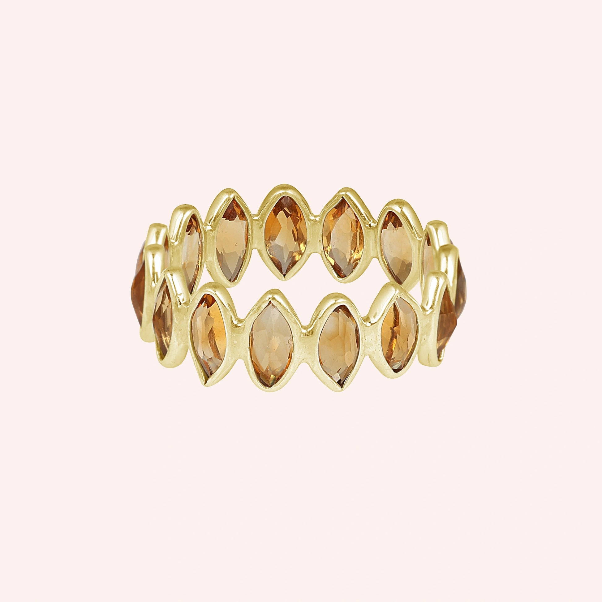 Gold vermeil citrine ring featuring beautiful marquise stones an eternity design on a light pink background straight on view