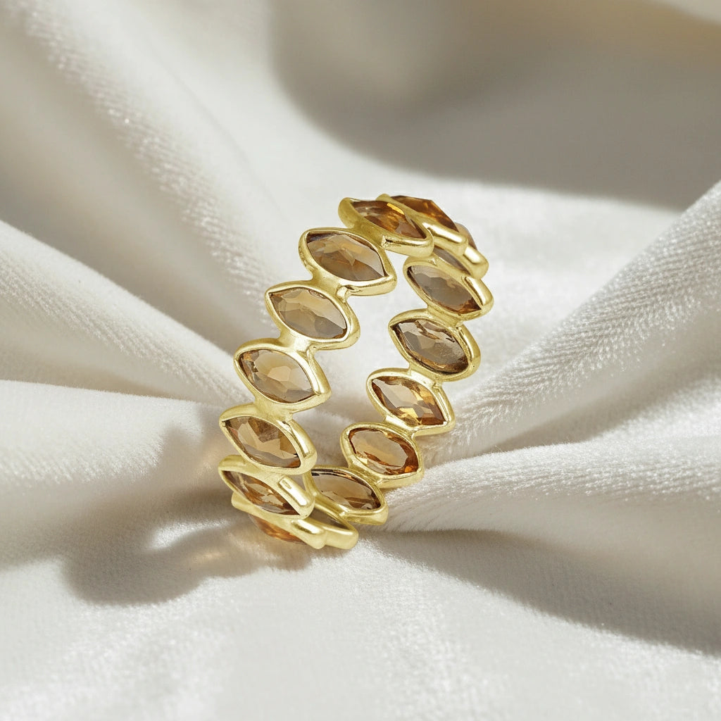 Gold vermeil citrine eternity ring with marquise stones on a wrinkled off white velvet background angled for depth.