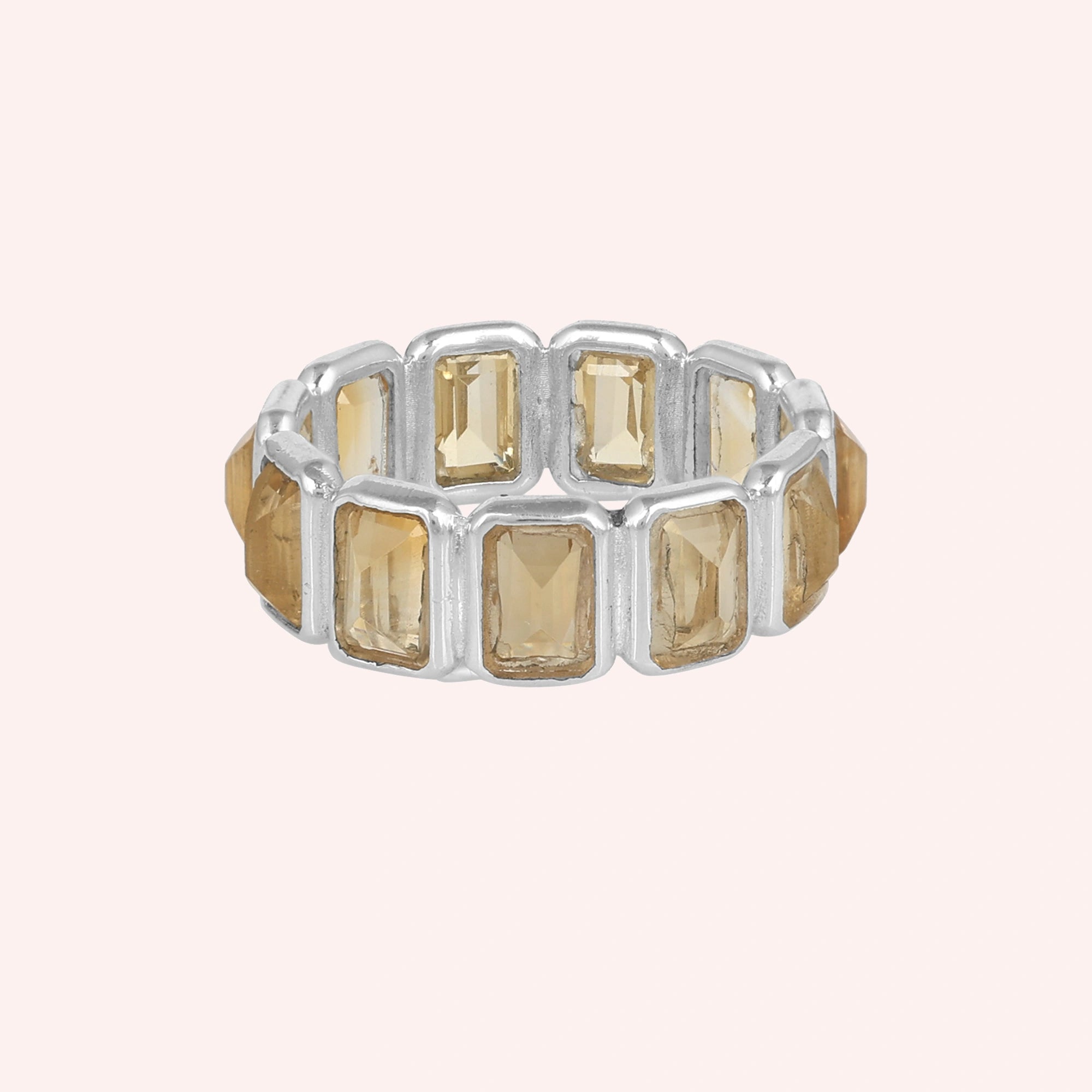 Horizontal shot of a sterling silver citrine ring on a light pink background showcasing rectangular citrine stones in a silver setting.