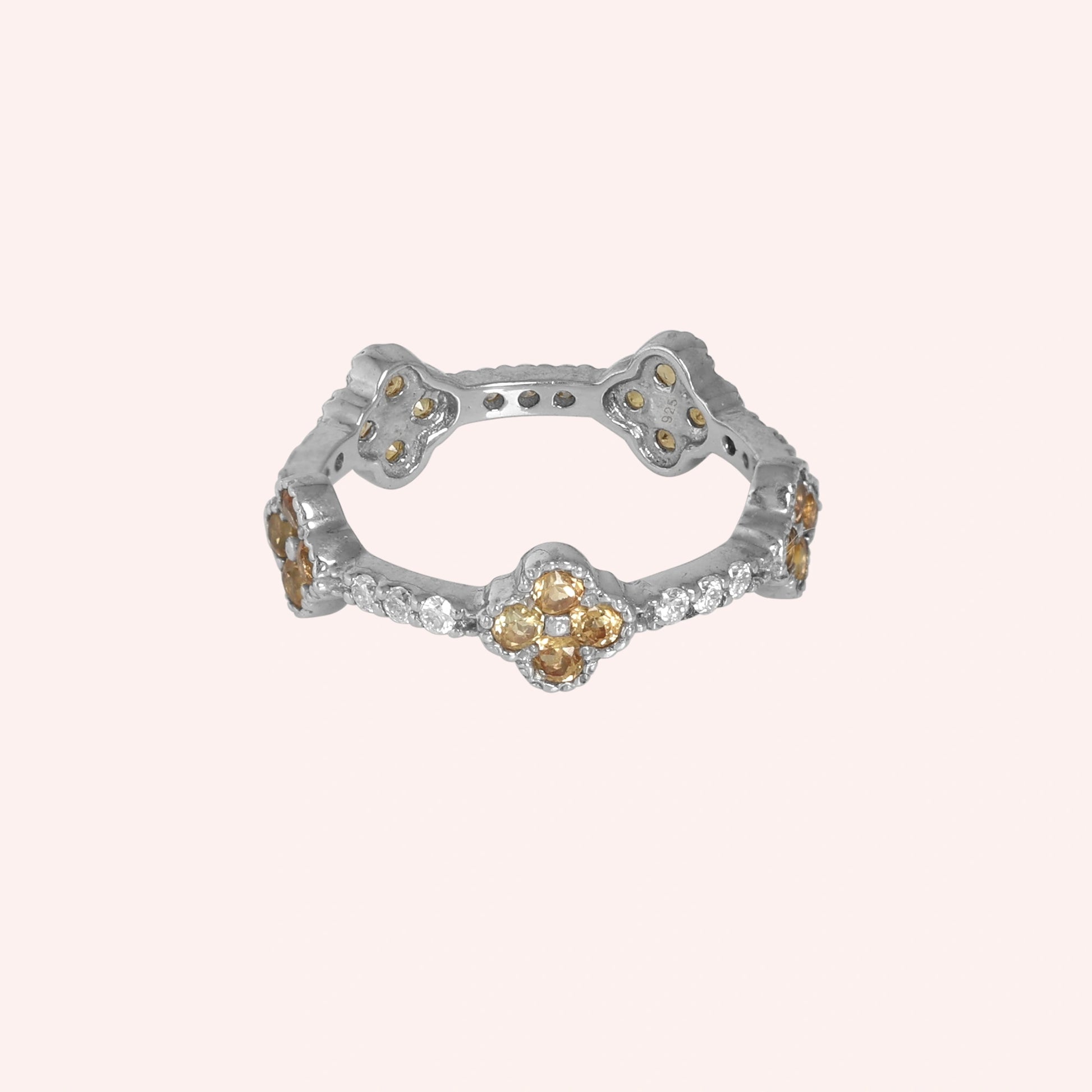Citrine_ring_sterling_silver_floral_band_with_citrine_and_white_topaz_in_front_angle_view_on_solid_pink_background