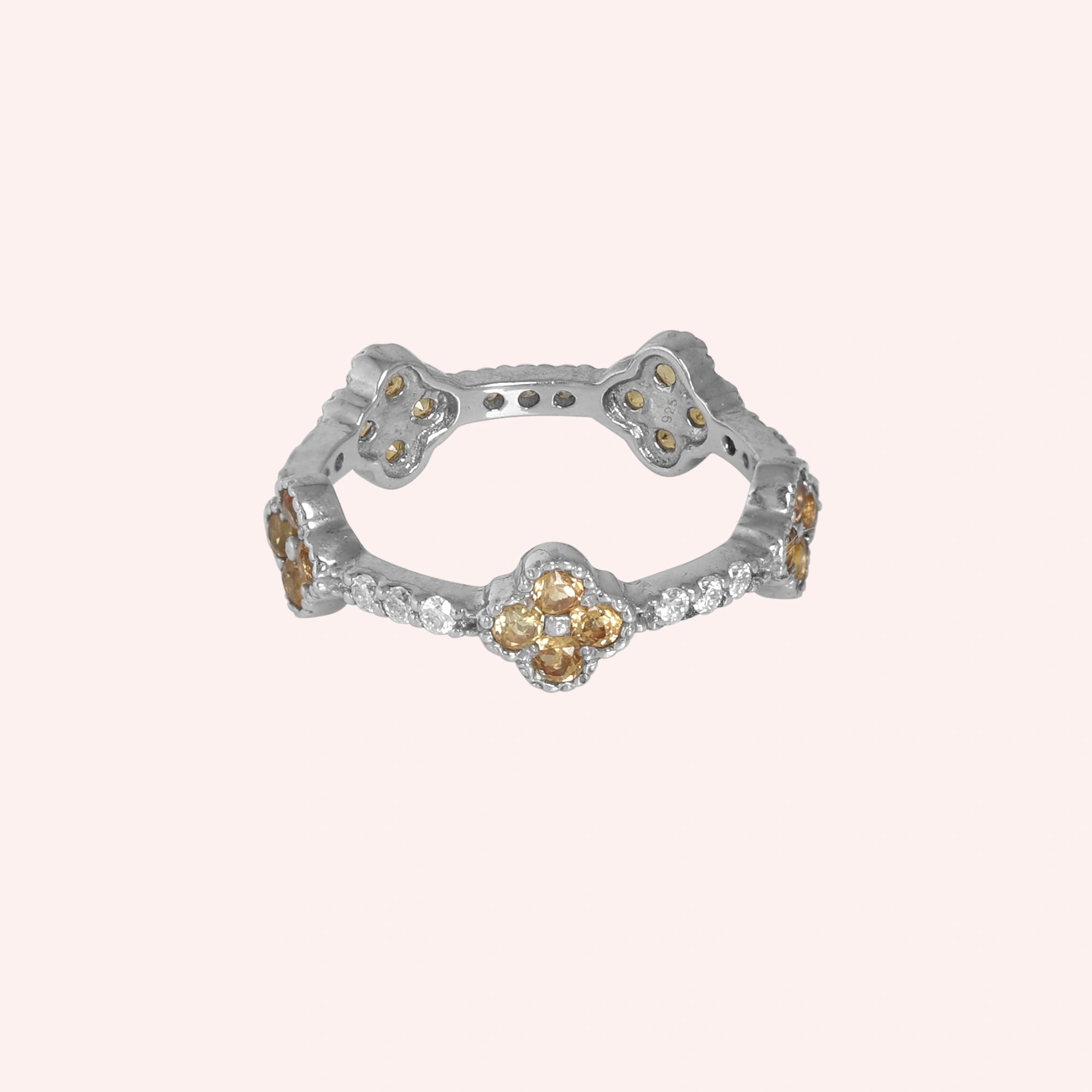 Citrine_ring_sterling_silver_floral_band_with_citrine_and_white_topaz_in_front_angle_view_on_solid_pink_background