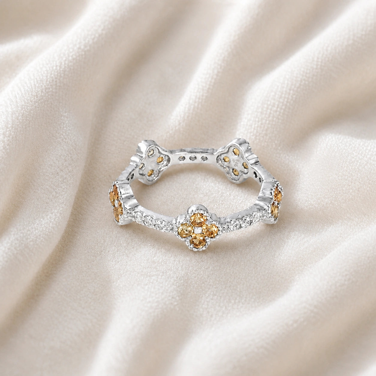 Citrine_ring_sterling_silver_floral_band_with_citrine_and_white_topaz_in_front_angle_view_on_soft_fabric_background