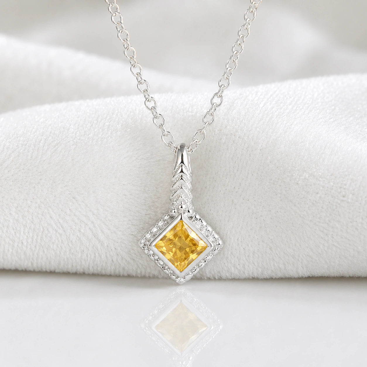 Birthstone_necklace_in_sterling_silver_with_square_cut_citrine_pendant_in_front_angle_view_on_soft_white_fabric_background