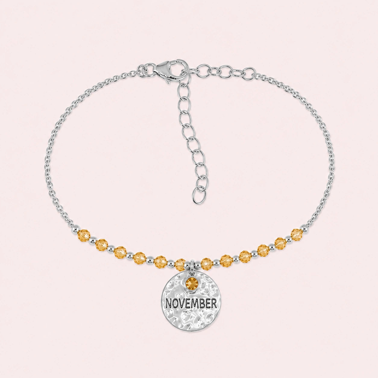 Birthstone_bracelet_in_sterling_silver_with_November_charm_and_citrine_beads_on_fine_chain_on_solid_pink_background