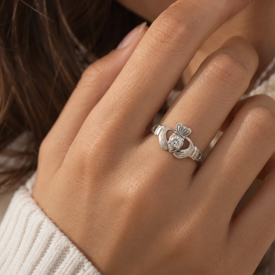 Claddagh_ring_in_gold_plated_silver_with_a_round_lab_grown_diamond_stone_at_front_angle_view_on_soft_fabric_background