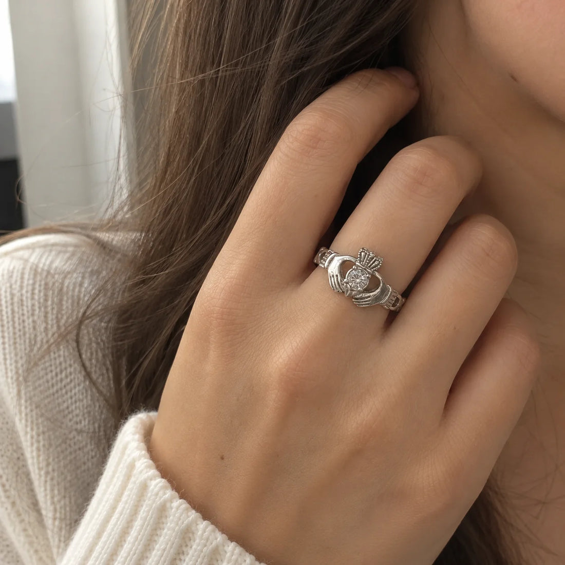 Claddagh_ring_in_gold_plated_silver_with_a_round_CZ_stone_at_front_angle_view_on_soft_fabric_background