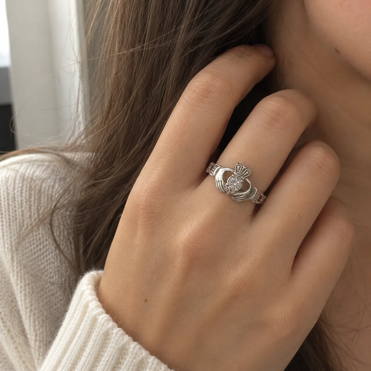 Claddagh_ring_in_sterling_silver_with_a_round_CZ_stone_at_front_angle_view_worn_by_a_model