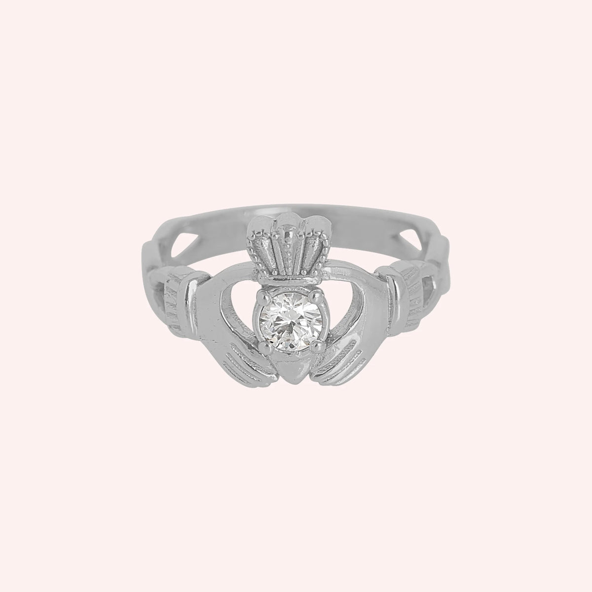 Claddagh_ring_in_sterling_silver_with_a_round_CZ_stone_at_front_angle_view_on_solid_pink_background