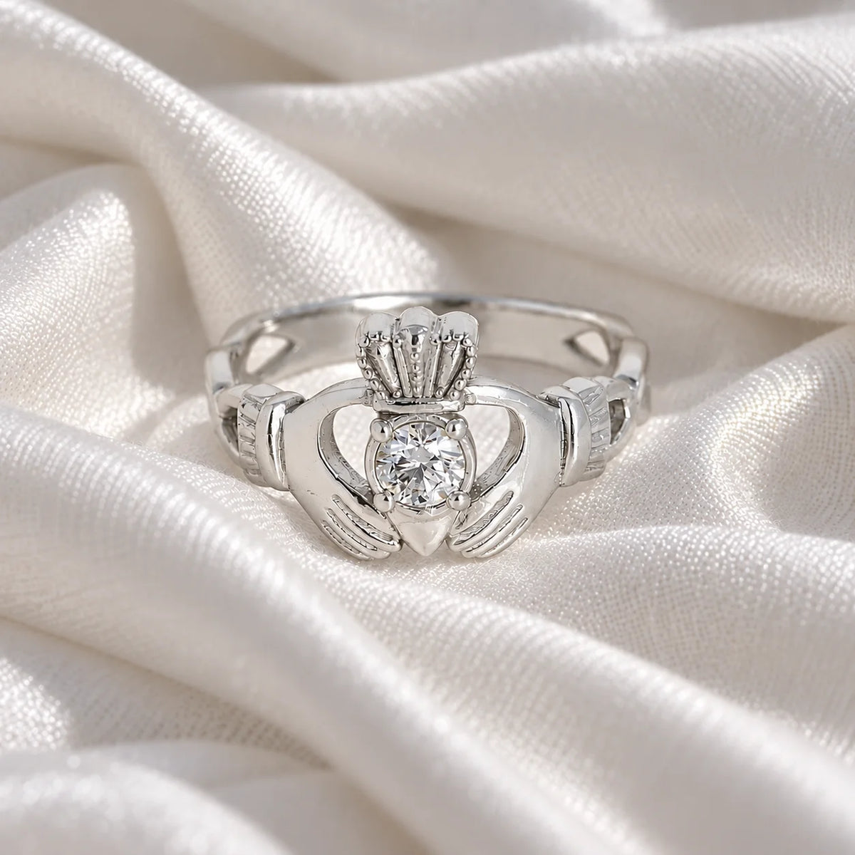 Claddagh_ring_in_sterling_silver_with_a_round_lab_grown_diamond_stone_at_front_angle_view_on_soft_fabric_background