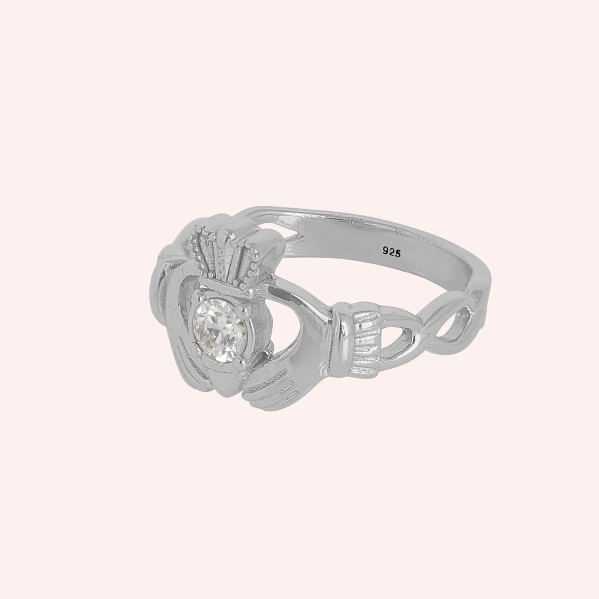 Claddagh_ring_in_sterling_silver_with_a_round_CZ_stone_at_side_angle_view_on_solid_pink_background