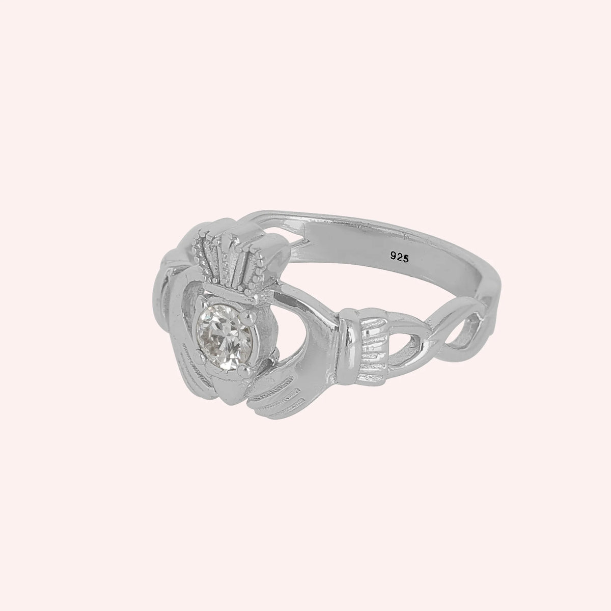 Claddagh_ring_in_sterling_silver_with_a_round_lab_grown_diamond_stone_at_slight_angle_view_on_solid_pink_background