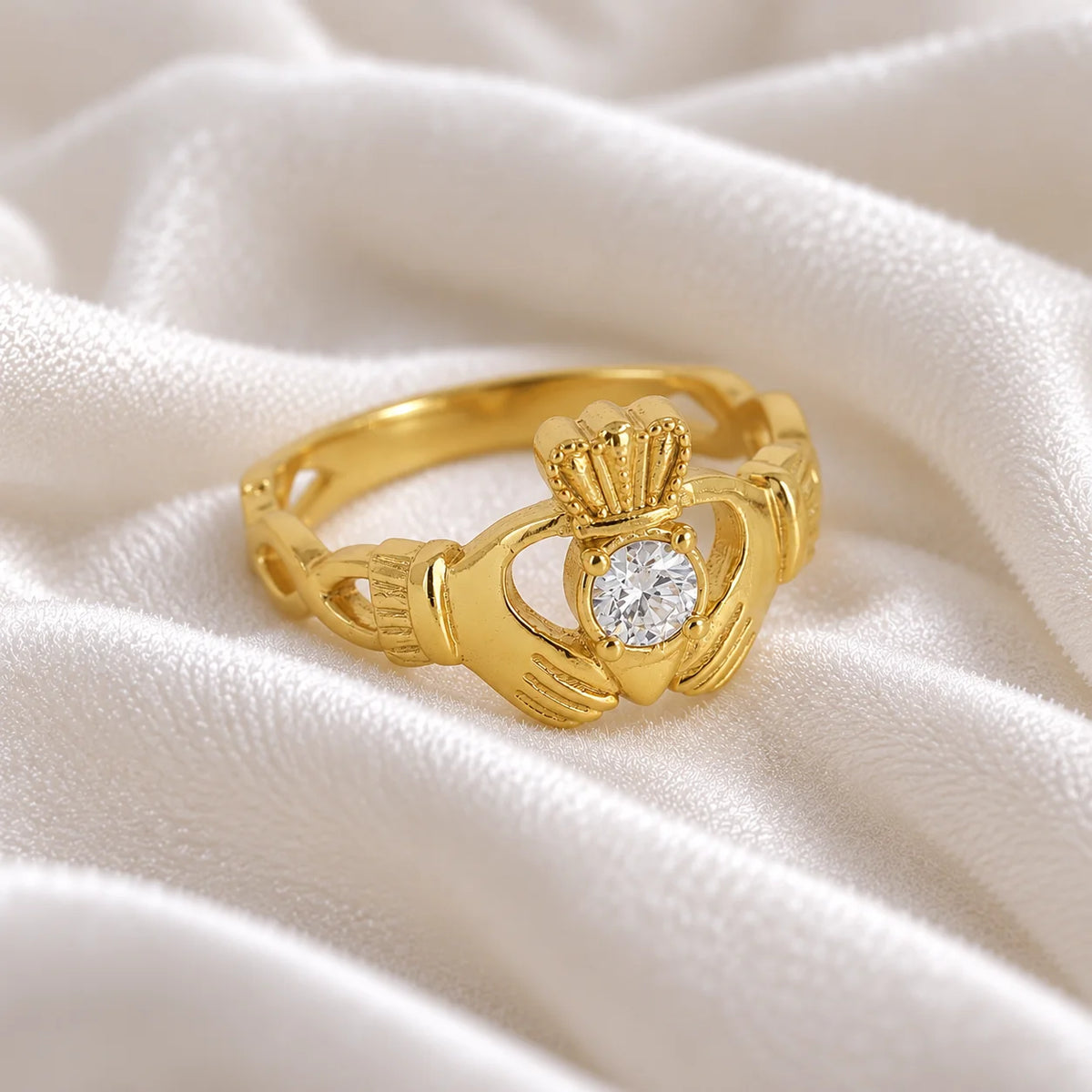 Claddagh_ring_in_gold_plated_silver_with_a_round_CZ_stone_at_side_angle_view_on_soft_fabric_background