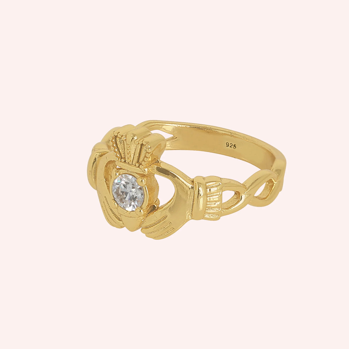 Claddagh_ring_in_gold_plated_silver_with_a_round_lab_grown_diamond_stone_at_slight_angle_view_on_solid_pink_background